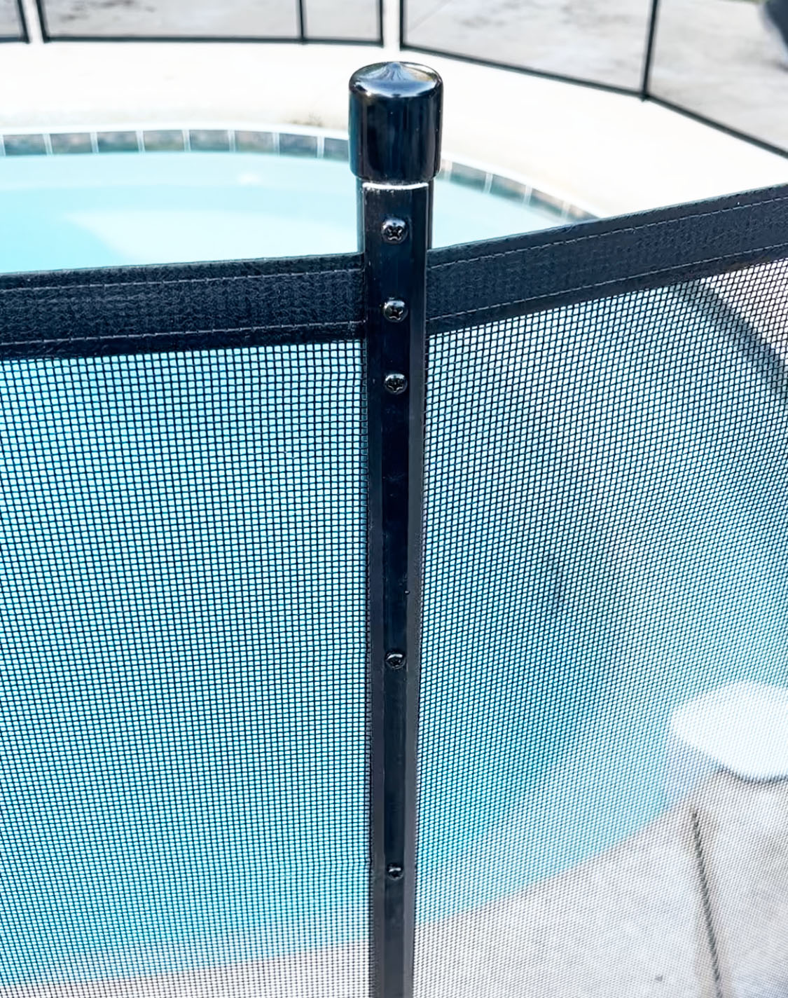 Old style pool fence post with screws and molding strips connecting mesh to post.
