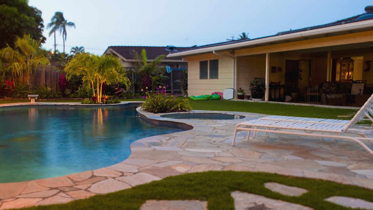 Backyard pool at dusk behind a home